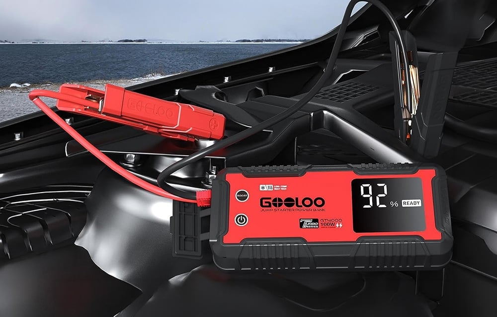 Car starter connected with clamps to the battery in the engine compartment