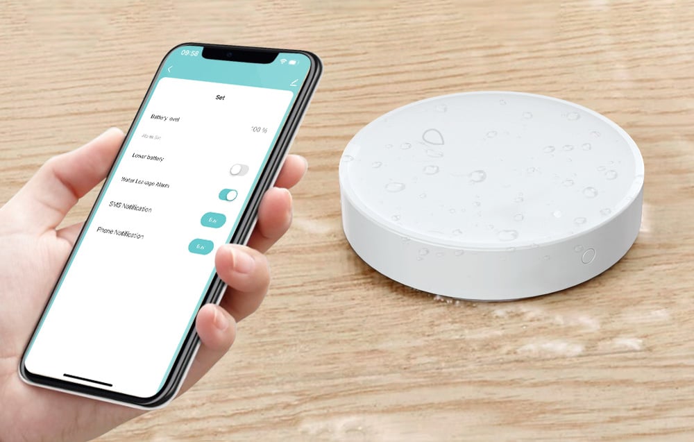 Close-up of the circular flooding sensor with water droplets on the housing and smartphone with notification settings