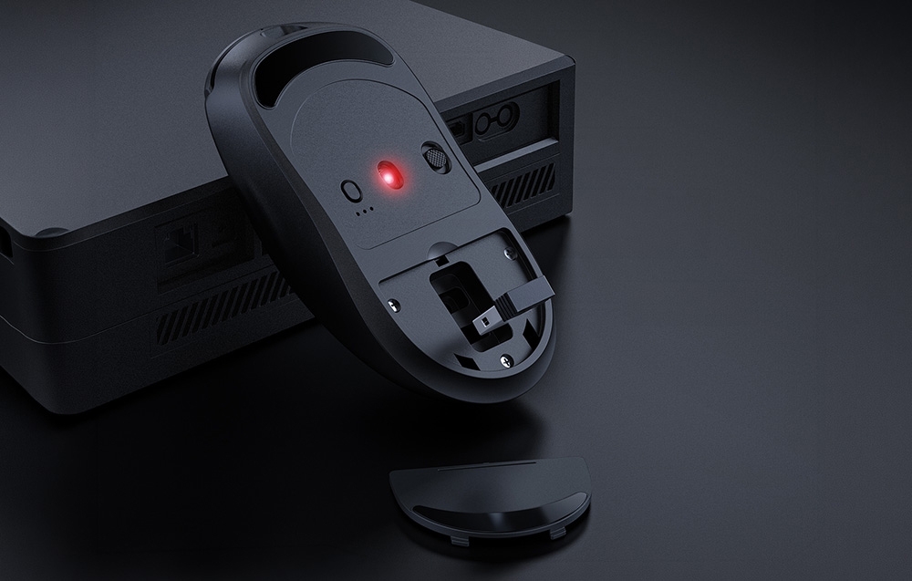 Upside-down computer mouse resting on a computer with a compartment for the USB receiver
