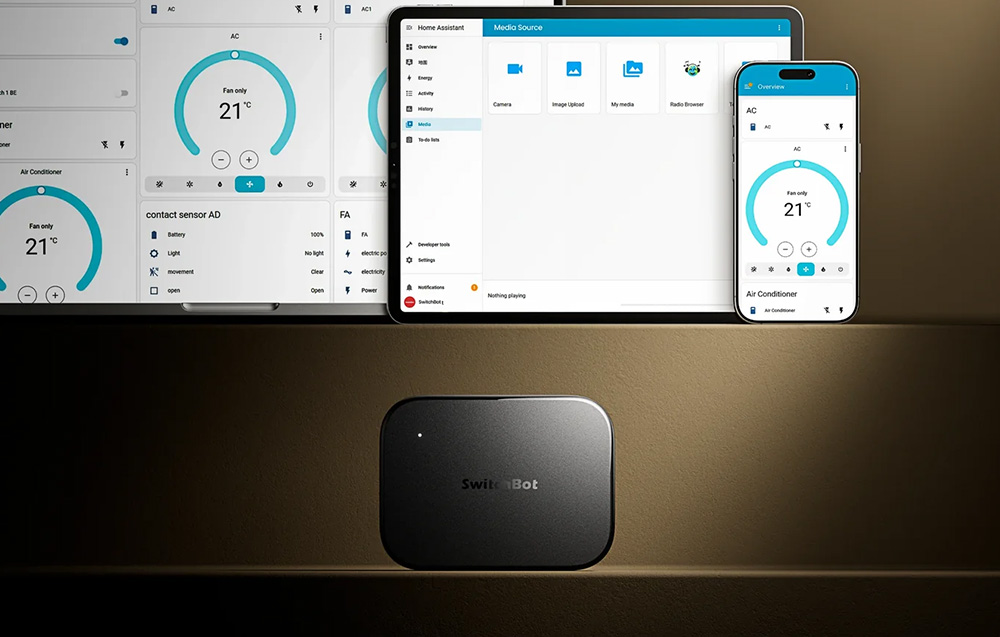 A SwitchBot gateway on a dark background, with screens above it showing the smart home control interface on a tablet and smartphone.