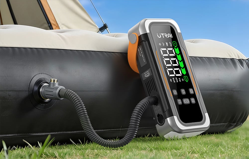 A car starter is pumping air into a black-and-white camping mattress.