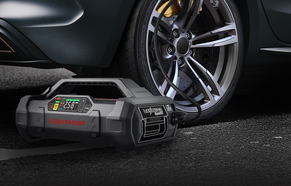 Device standing next to a car wheel while inflating a tire with a black hose.
