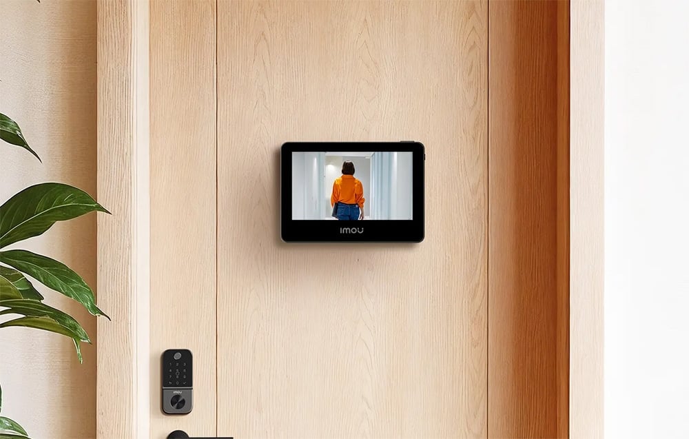 Imou door viewer screen mounted on a light-colored door, displaying a woman in an orange shirt in the hallway