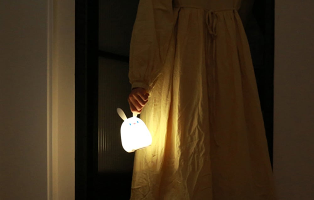 SuperFire RAB-02 Little Rabbit night light held by a person wearing a nightgown.