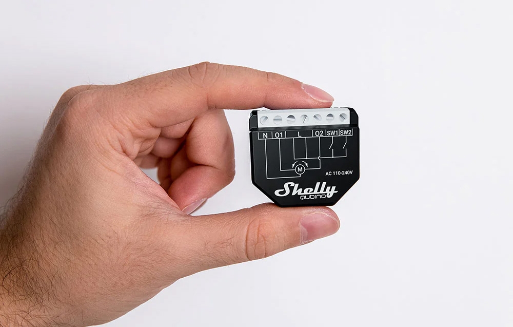 A view of a hand holding a black electrical control unit against a solid white background.