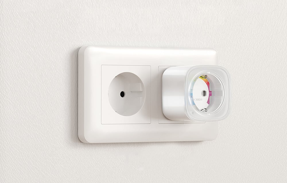A smart outlet plugged into one of two double wall outlets on a bright wall