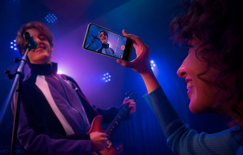 A woman recording a guitarist with a Hotwav smartphone