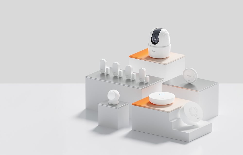 A set of white Imou smart home devices, including a pan-tilt camera and sensors, mounted on white stepped platforms
