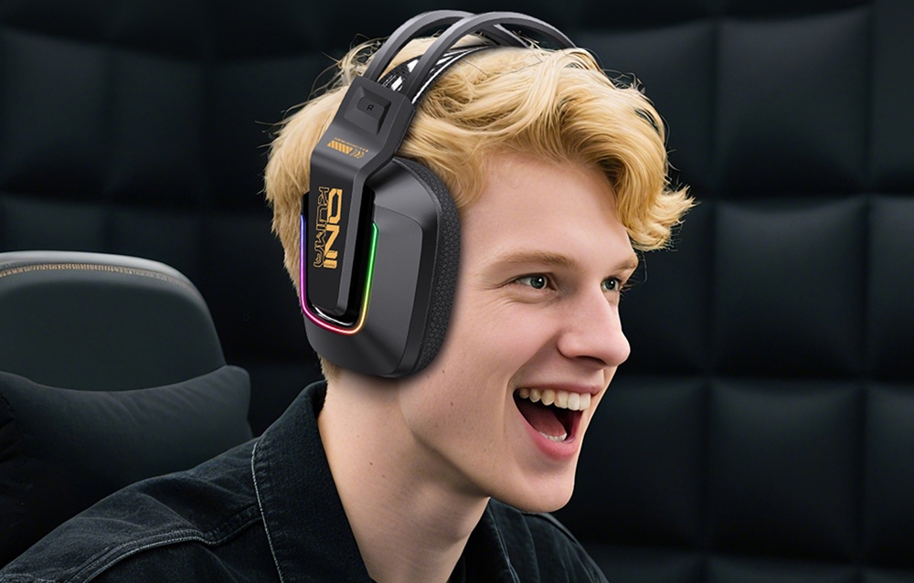 Smiling young man with blonde hair wearing black gaming headphones with RGB backlighting