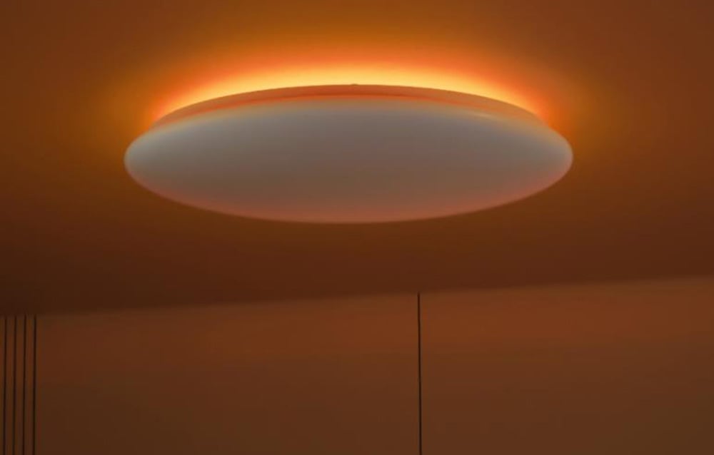 Okrągła sufitowa lampa LED świecąca na pomarańczowo z efektem aureoli.