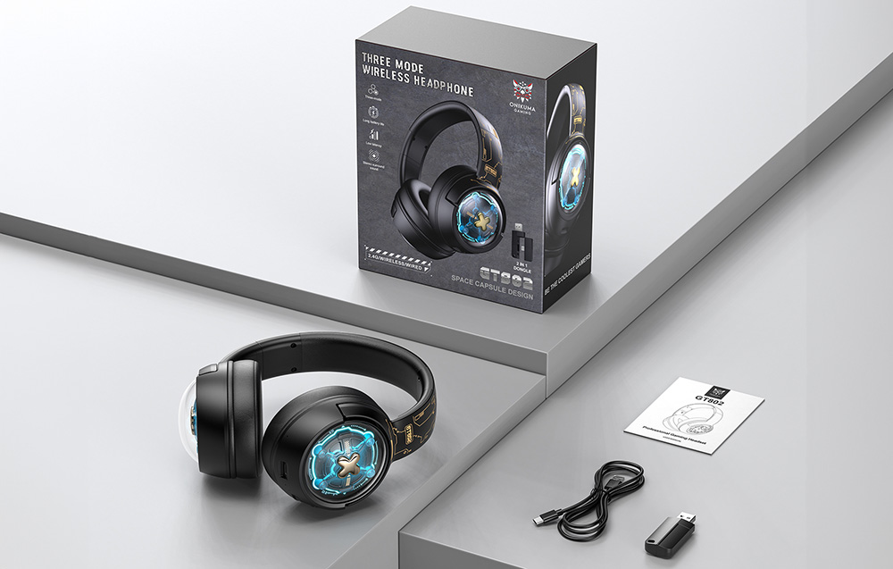 Onikuma gaming headphones lying on a gray desk next to a box, user manual, cable, and USB adapter