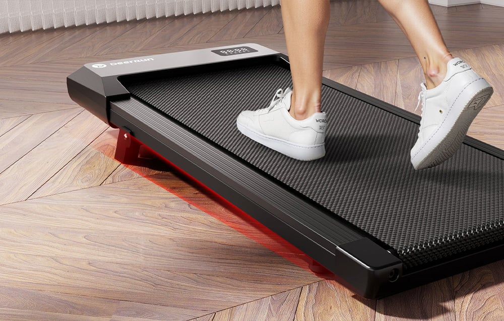 Close-up of a foot in a white shoe on a textured treadmill surface with red backlighting