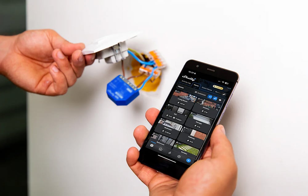 Installation of the blue controller in a wall box using a phone with the mobile app open.