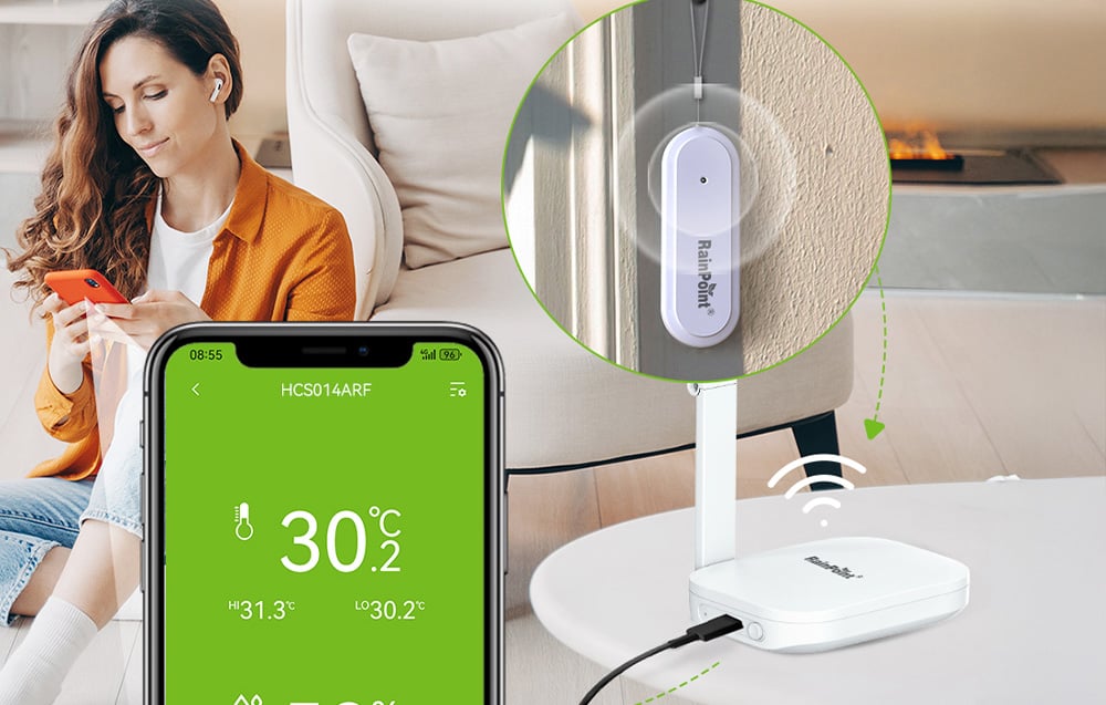 A woman uses a smartphone with the RainPoint app in the living room, where the base station and a sensor graphic on the wall are visible