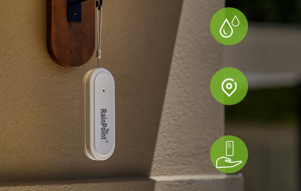A white RainPoint outdoor sensor hangs on a string near the wall next to three green icons representing humidity, location, and a device in the hand