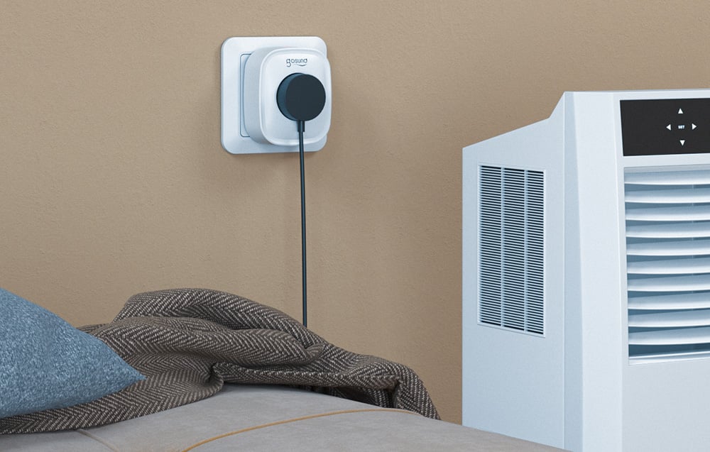 Gosund smart plug with a connected cord next to the bed, connected to a portable air conditioner