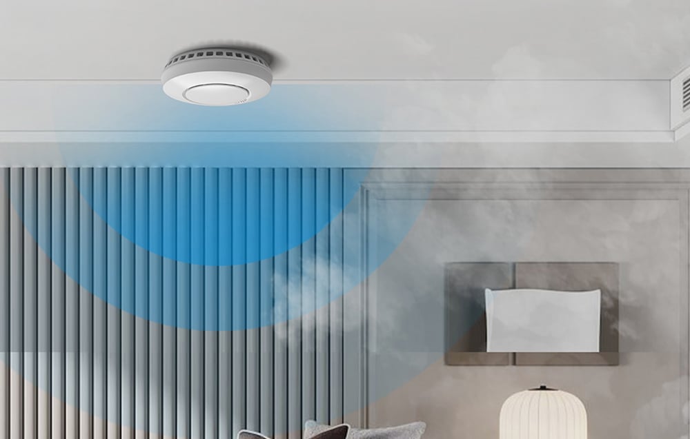 A white smoke detector mounted on the ceiling in an elegant bedroom with blue mist symbolizing smoke detection