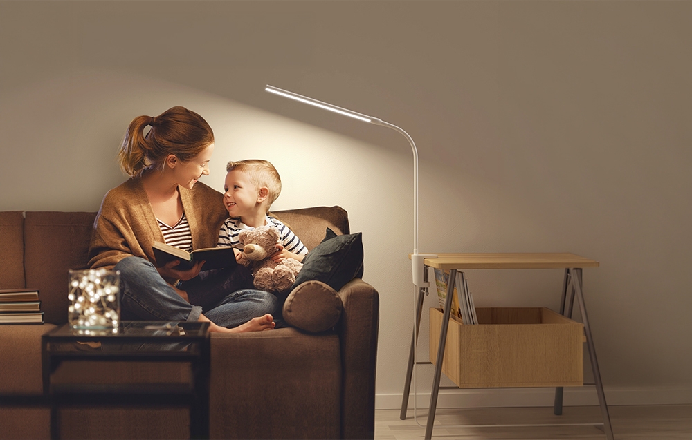 In the light of the desk lamp, a woman and a boy sit side by side reading a book