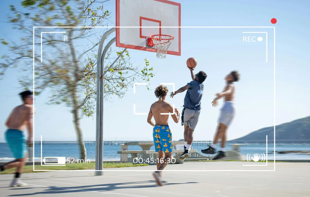 View from the perspective of the camera in the glasses of a group of people playing basketball on a seaside court.
