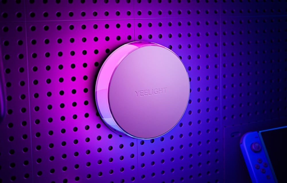 Close-up of the Yeelight Vega night light mounted on a perforated wall, backlit with purple light.