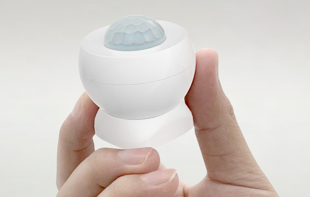 Close-up of motion sensor held in fingers on neutral background