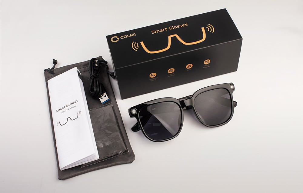 Set containing black smart glasses, a box, a user manual, a case, and a charging cable.