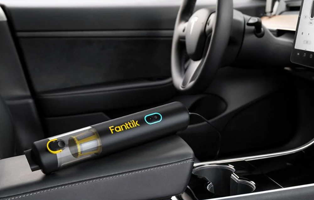 The cordless car vacuum cleaner lies on the armrest plugged in for charging.