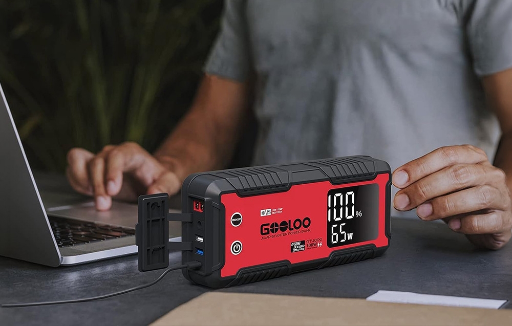 Car starter connected to a laptop on a desk, used as a power source