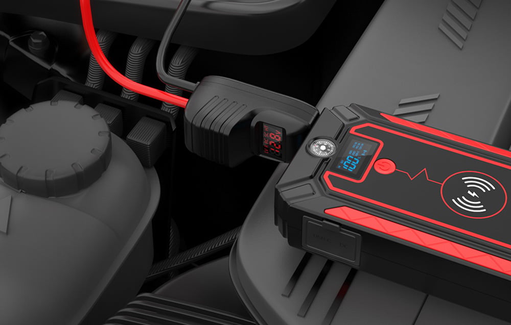 A close-up of a car starter connected via a special plug with a display under the hood of a car.