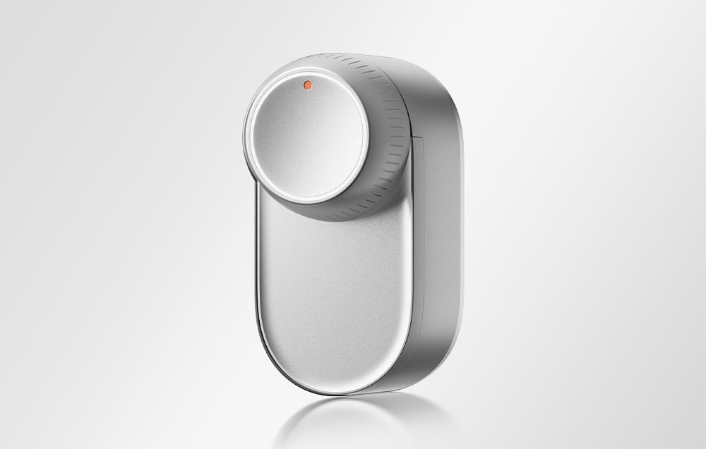 SwitchBot smart lock in silver housing with round knob at the top and orange LED indicator