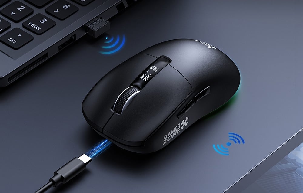 Close-up of the Onikuma gaming mouse with a cable next to a laptop on a dark desk