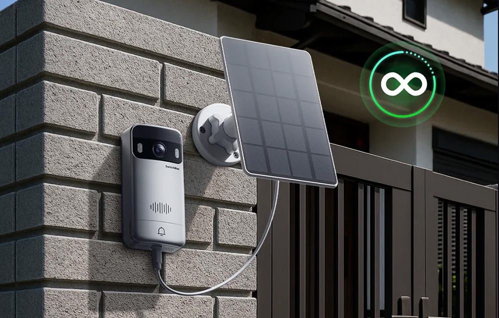 A doorbell mounted on a wall, connected by a cable to a small solar panel next to it.