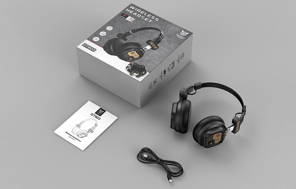 Gaming headphones lying on a gray table next to a box, user manual, and USB cable