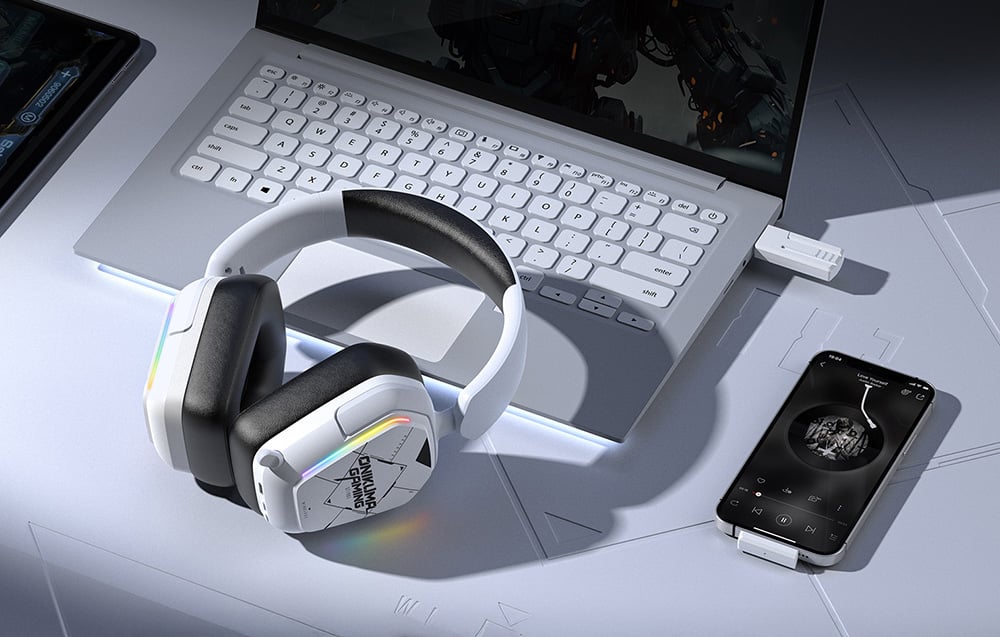 White Onikuma headphones on a white desk next to a laptop, smartphone and tablet