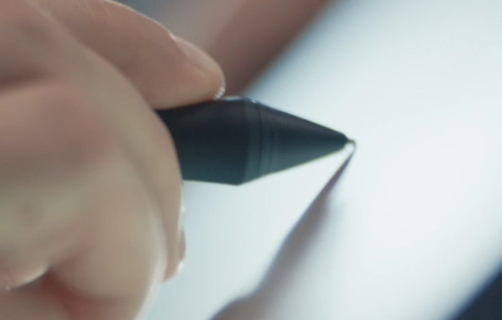 Hand holding black stylus with rubber grip on white background