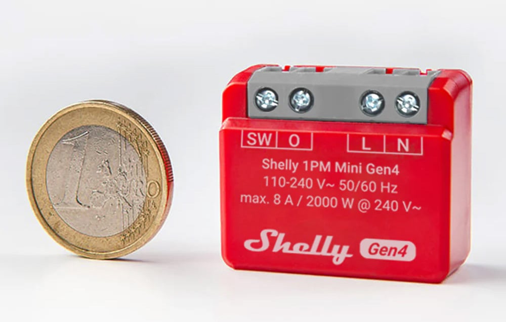 A red Shelly controller placed next to a one-euro coin for product scale comparison.