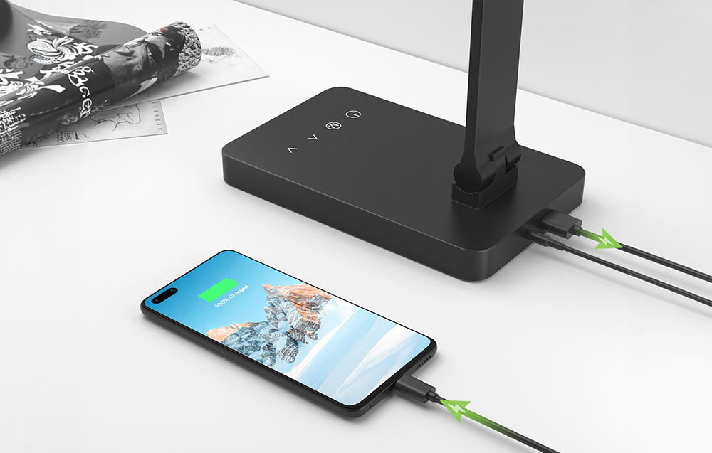 A smartphone plugged into a black lamp on a white table to charge