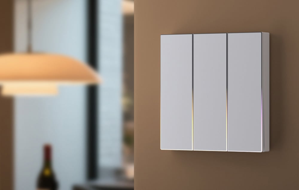 Triple white touch switch with soft illumination mounted on a beige wall in the interior