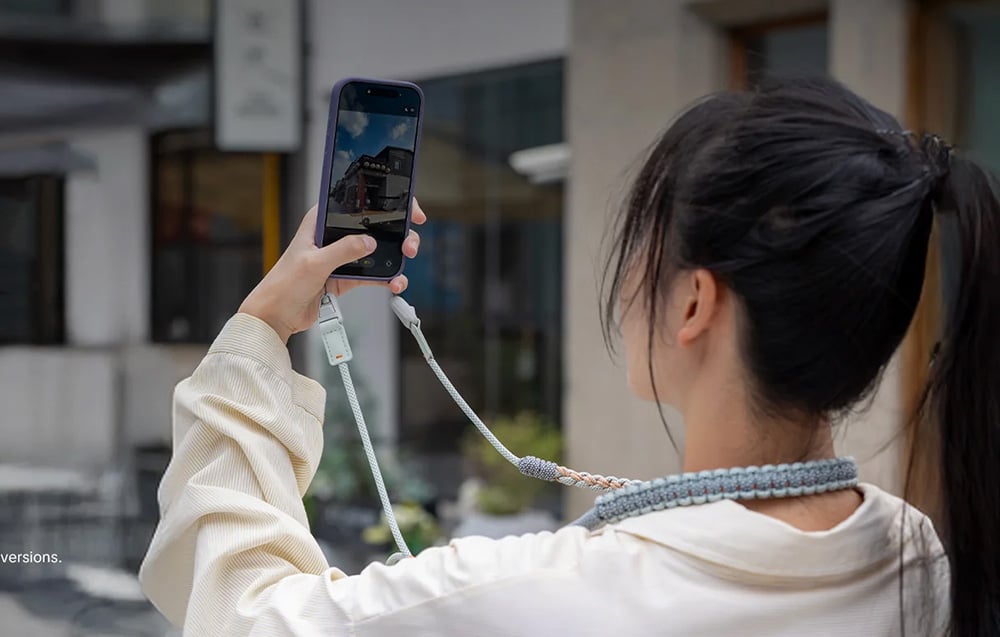 Black-haired woman photographs building with smartphone mounted to PGYTECH belt