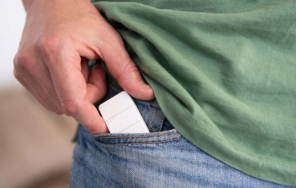 Small white remote control removed from a jeans pocket