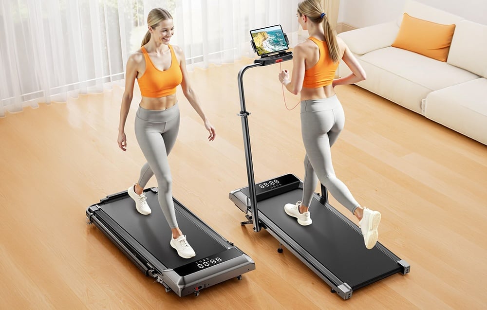 Two women with blonde hair in athletic attire are running on treadmills in a bright living room