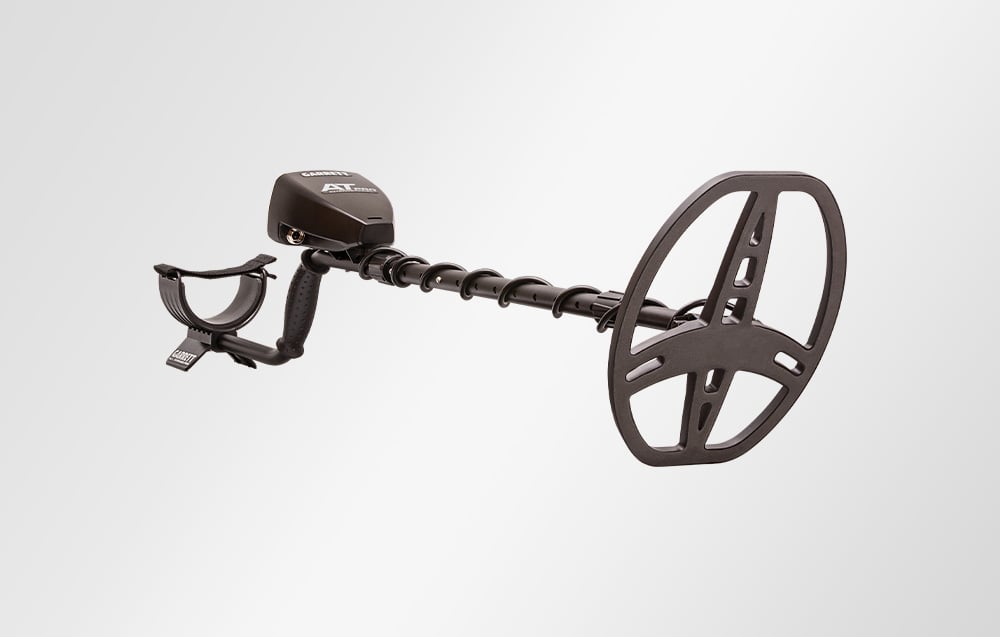 Metal detector with coil seen from the side against a bright background.