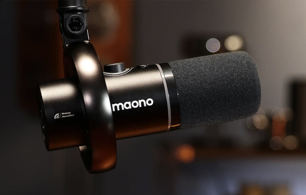 A black Maono microphone mounted on a shock mount, side view against a dark background