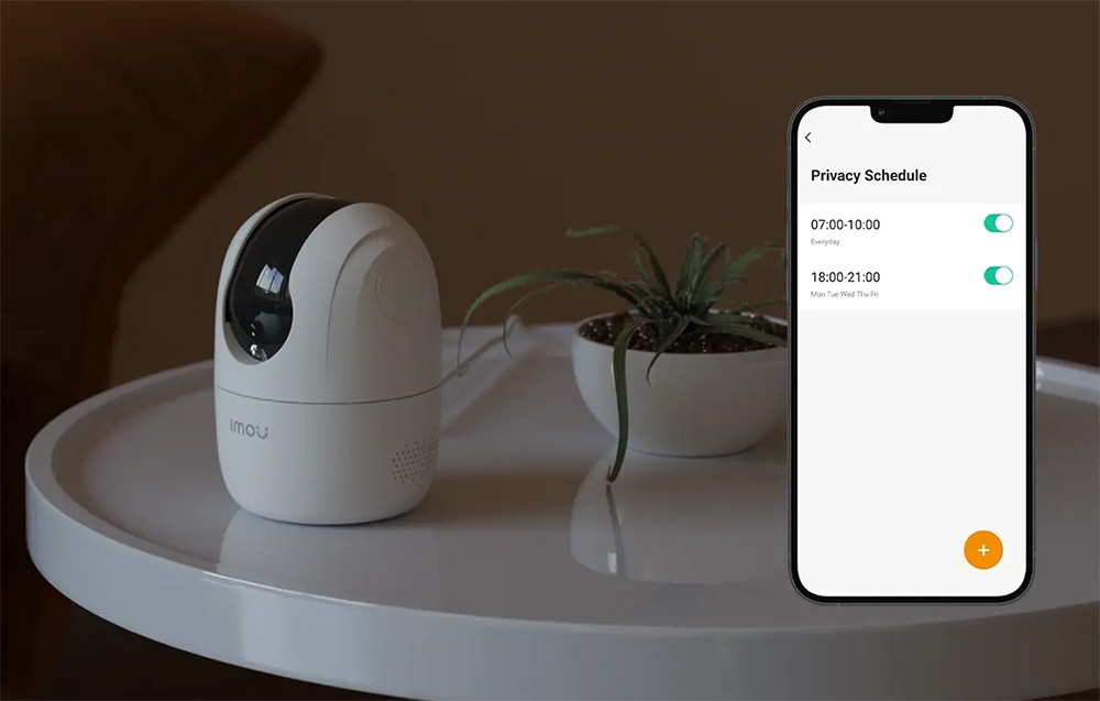 A camera on a table next to a phone displaying the Privacy Schedule screen with the times 7:00 AM–10:00 AM and 6:00 PM–9:00 PM set