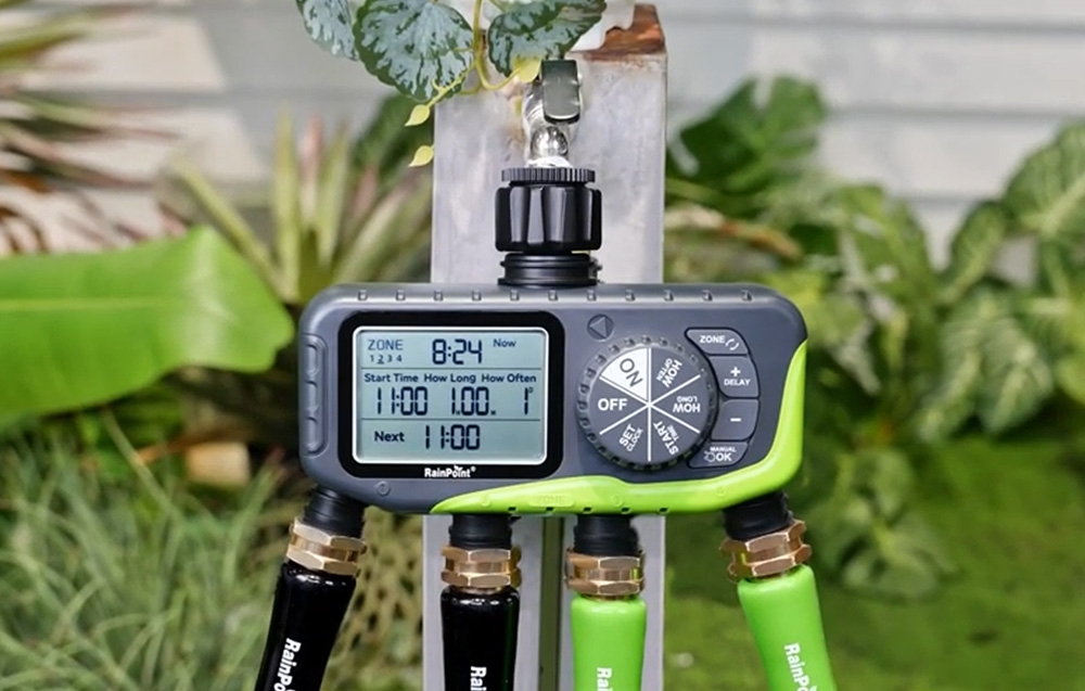 RainPoint 4-zone irrigation controller connected to an outdoor faucet, with 4 hoses connected at the bottom in the garden