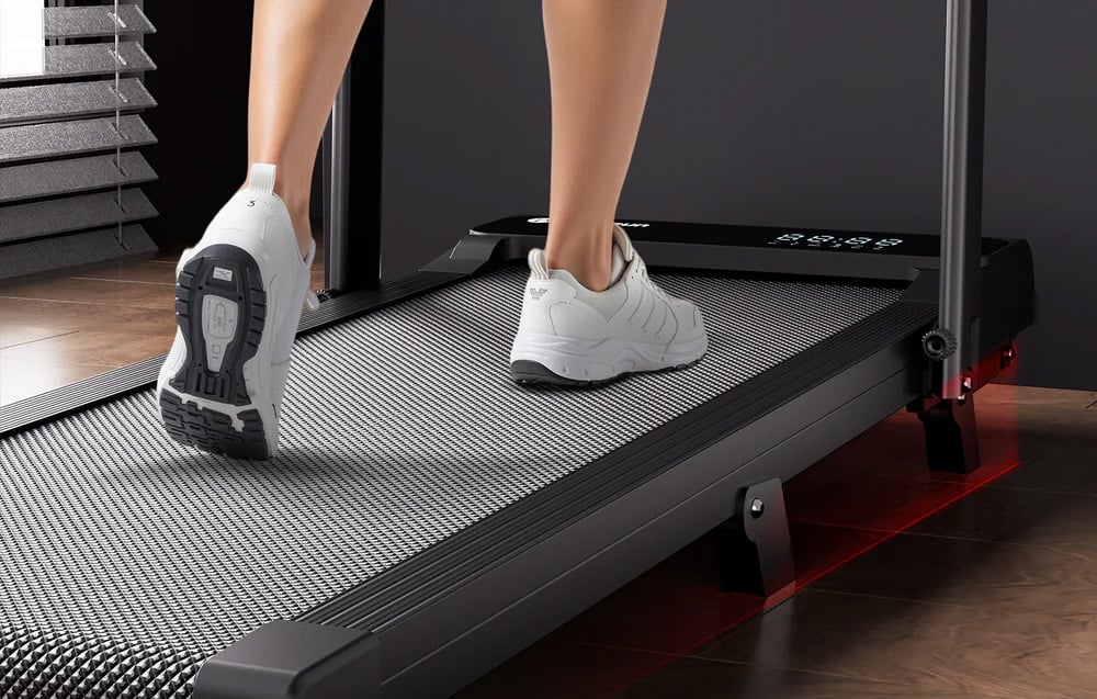 Close-up of white sneakers on the textured surface of the treadmill with red backlighting