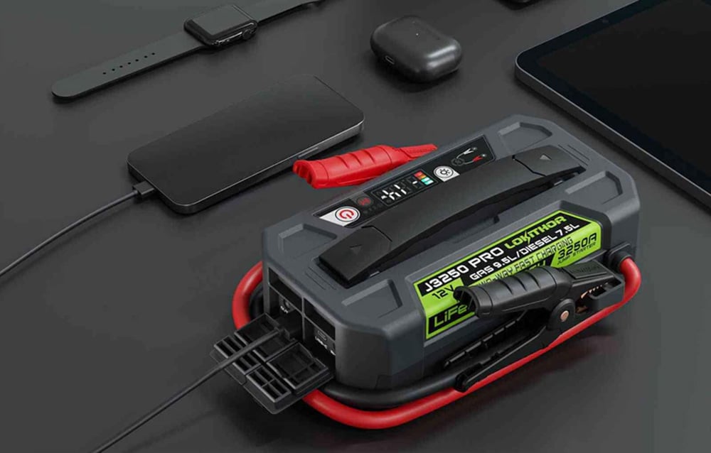 Lokithor J3250 Pro serving as a power bank charging a smartphone next to headphones and a tablet on a desk.
