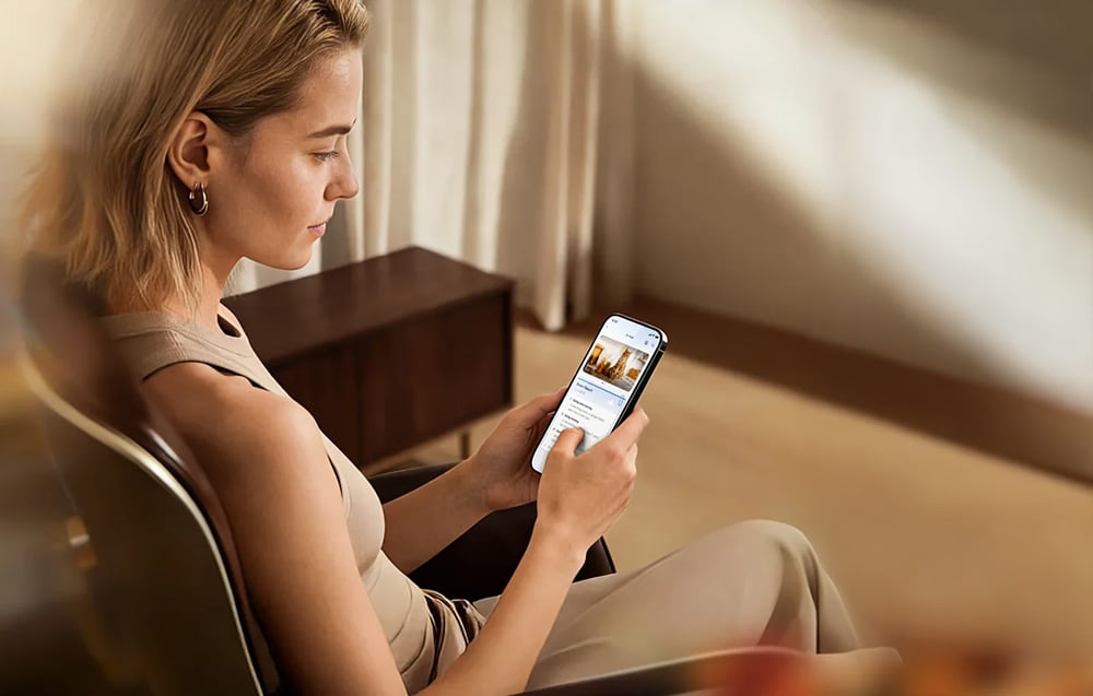 A woman sitting in an armchair using a smartphone in a home interior.