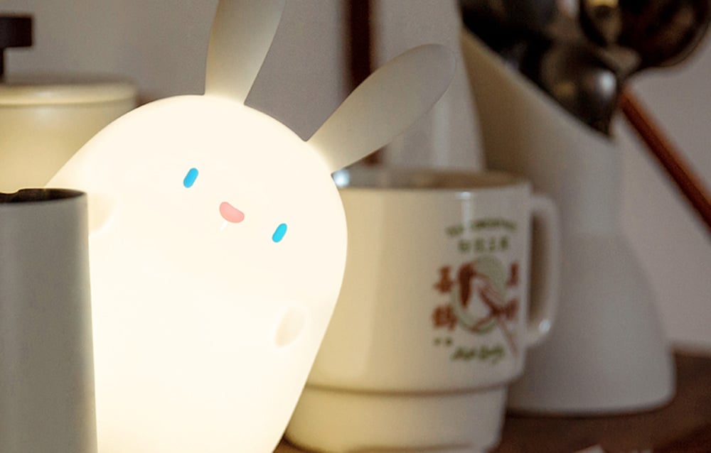 SuperFire RAB-02 Little Rabbit bedside lamp hidden behind white porcelain, shining bright light.